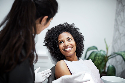 Dentist discussing cosmetic options with smiling female patient at Roy C. Blake III, DDS, MSD, Maxillofacial Prosthodontist in Jupiter, FL