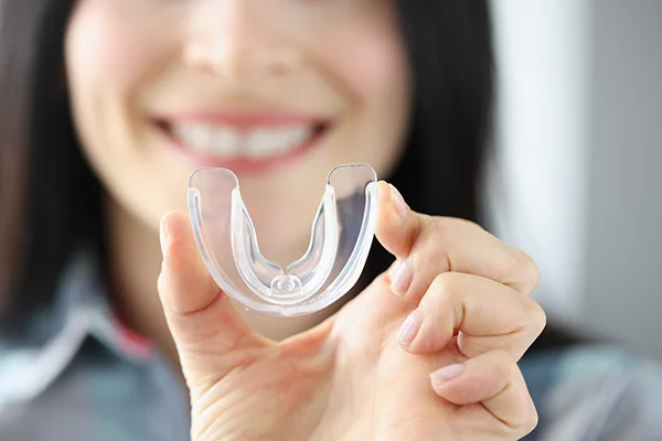 Close up of a simple night mouth guard being held up by a patient at Roy C. Blake III, DDS, MSD, Maxillofacial Prosthodontist in Jupiter, FL 